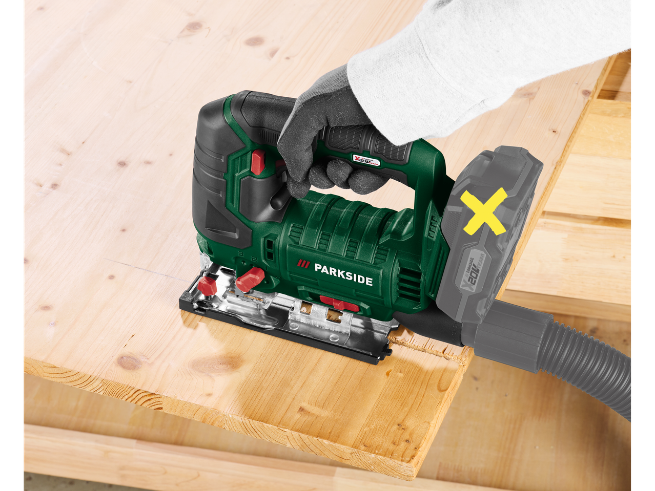 Person using a Parkside jigsaw to cut wood, with a dust extraction hose attached.
