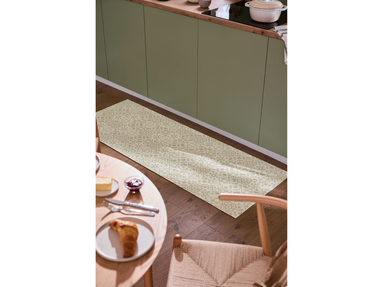 Livarno köögivaip mustrilise disainiga puitpõrandal roheliste kappide kõrval.