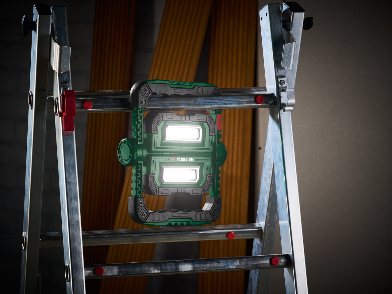 Работна лампа Parkside, закачена на стълба, осветяваща тъмна стая.