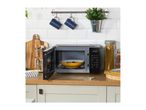 A microwave with an open door and a yellow bowl inside, surrounded by kitchen accessories.