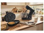 A waffle maker and a stand mixer on a kitchen counter with waffles and ingredients.