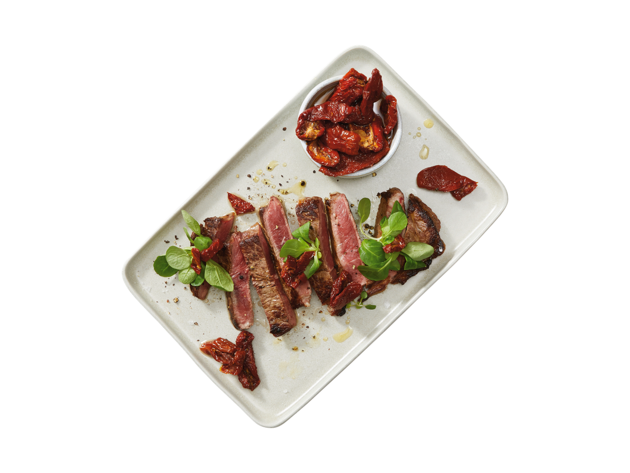 Italiamo sun-dried tomatoes and sliced steak on a plate.