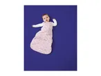 Baby in a pink star-patterned sleeping bag on a blue background.