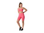 Woman in a pink ribbed sports bra and matching cycling shorts, smiling and looking to the side.