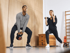 Mann und Frau trainieren mit Kettlebell und Hanteln in Sportkleidung.