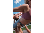 Mulheres em tops desportivos CRIVIT com ácido hialurónico, a fazer acroyoga ao ar livre.