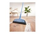 Blue broom sweeping white powder on a wooden floor in a living room.