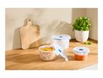 Three round plastic food storage containers on a wooden kitchen countertop.