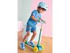 Boy in blue t-shirt and shorts, wearing a helmet, riding a scooter.