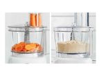 Food processor with carrots being sliced and processed into a fine meal.