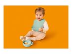 Happy baby in a bib, holding a snack, with a bowl of snacks nearby.