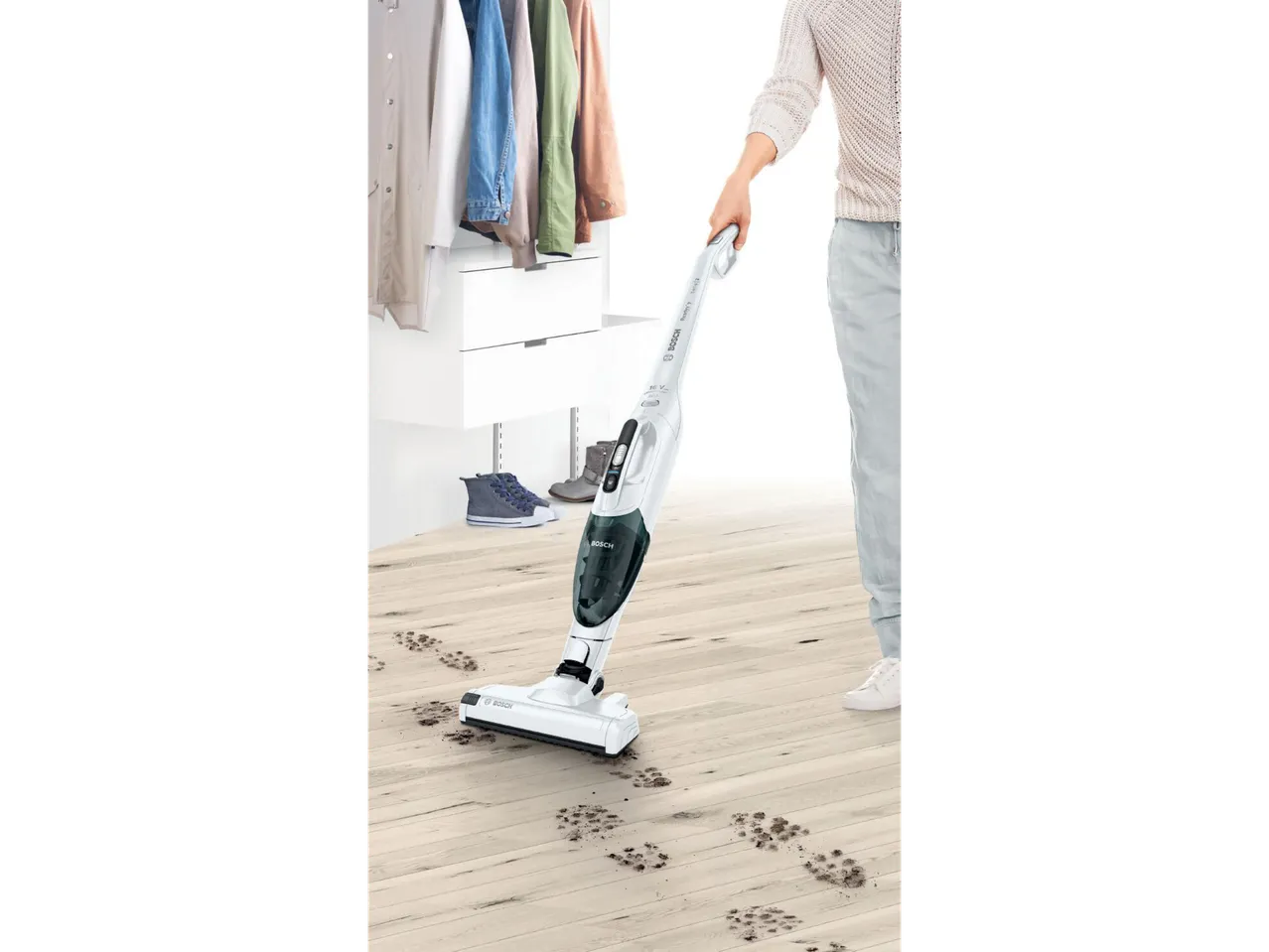 Bosch Cordless Vacuum Cleaner cleaning muddy footprints on a wooden floor in a closet.