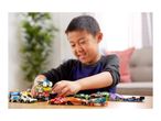 A boy playing with a collection of colorful toy cars on a wooden table.