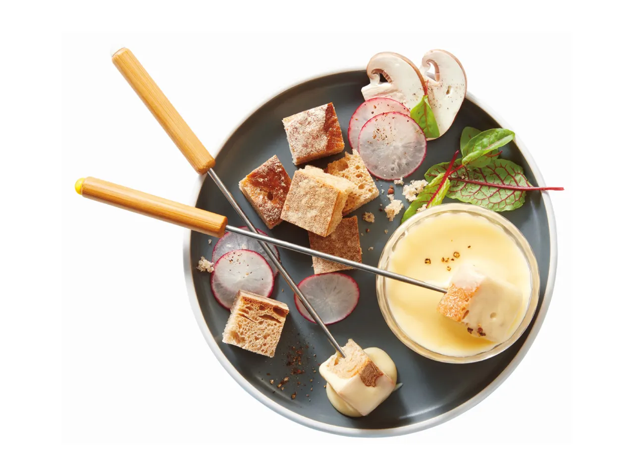 A plate of cheese fondue served with bread cubes, sliced radishes, mushrooms, and fresh greens.
