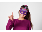 A girl in a purple Halloween felt mask smiles and points forward.