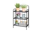 Black metal plant stand with potted herbs, flowers, watering cans, and gardening tools.
