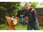 Bărbat în haine de lucru Parkside taie lemn cu drujba.