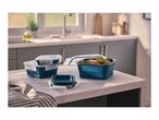 Collapsible food containers in a kitchen setting, one filled with vegetables.