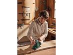 A woman uses a Parkside electric sander on a piece of wood in a workshop.