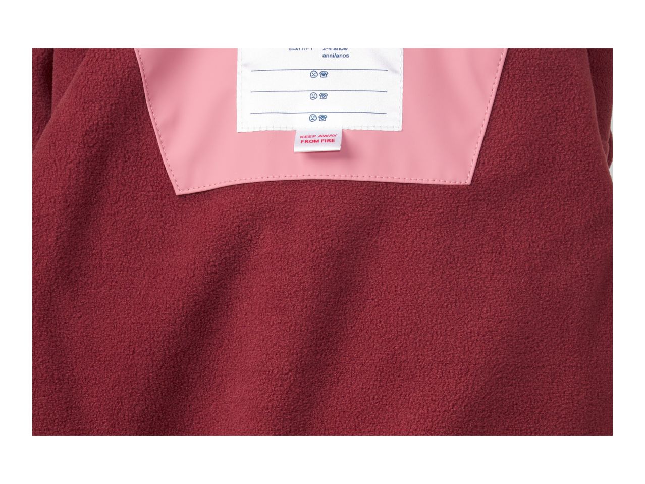 Close-up of a red fleece garment with a pink inner lining and a white label.