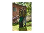 Man shredding garden waste with a green garden shredder in a sunny backyard.