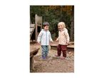 Two happy children in waterproof jackets and trousers playing in a puddle outdoors.