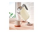 An electric kettle pouring hot water into a mug on a kitchen counter