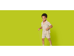 Smiling boy in a light beige short-sleeved shirt and shorts, holding ropes.