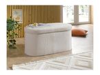 A cream-colored ottoman with a removable lid, magazines, and a small box on top.