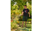 Homem a regar o jardim com uma mangueira, t-shirt PARKSIDE com 'YOU GOT THIS!' e berbequim.