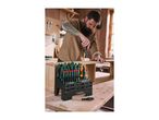 A man uses a screwdriver from a large set of screwdrivers and bits on a wooden workbench.