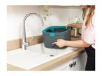 Woman draining water from a mop bucket into a kitchen sink.