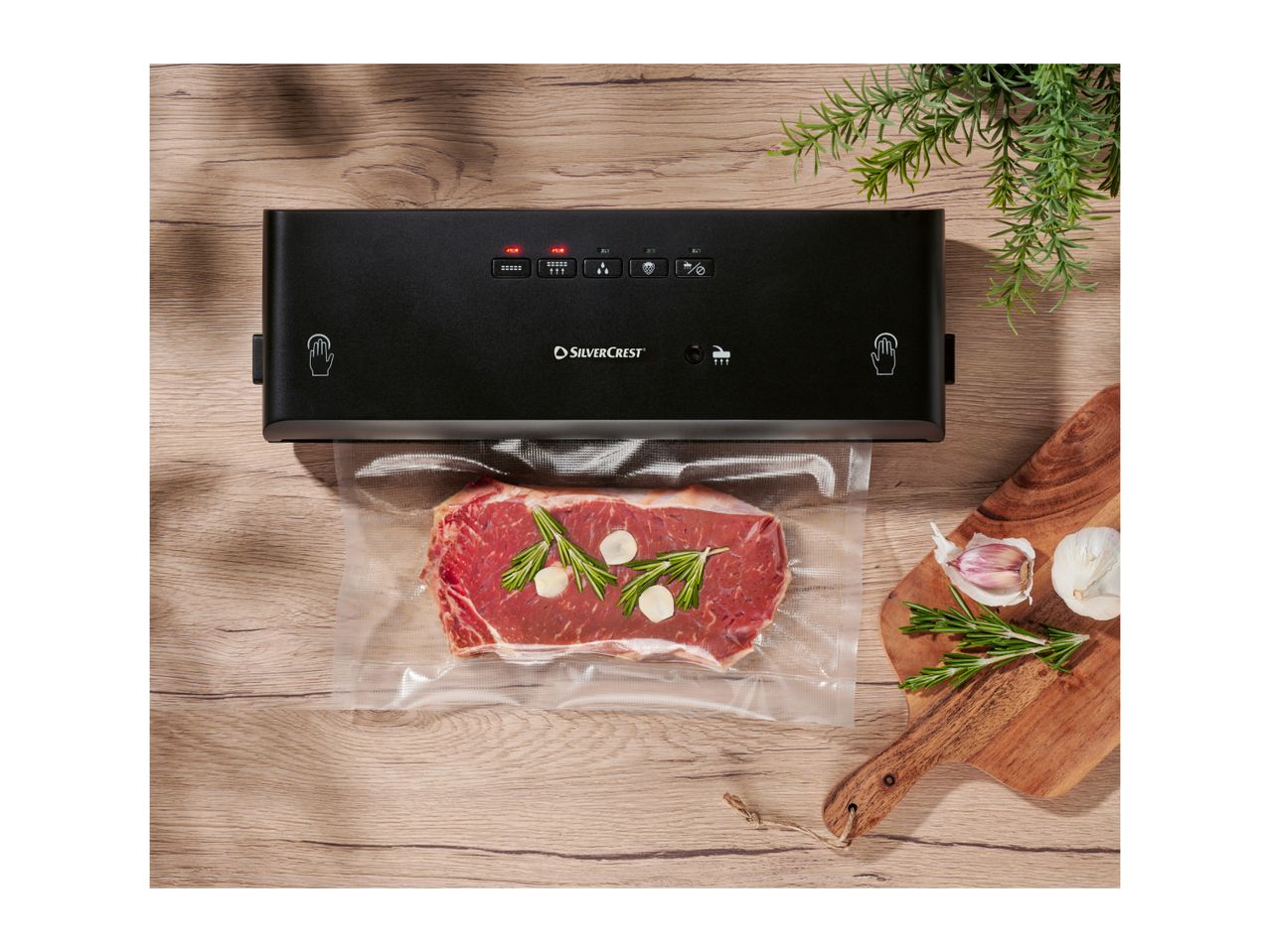 Silvercrest vacuum sealer with steak, rosemary, and garlic on a wooden surface.