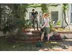 Man cleaning stairs with a pressure washer, woman trimming grass with a grass trimmer.