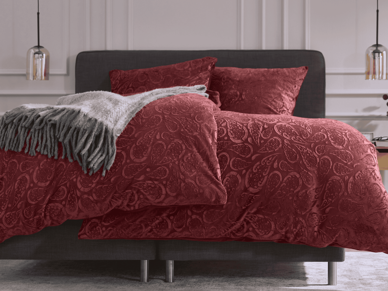 Bett mit roter Paisley-Bettwäsche und grauem Überwurf