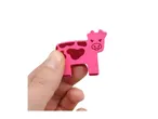 Hand holding a pink wooden cow toy with dark pink spots.