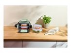 Green lunch bag with food containers filled with vegetables on a wooden counter.