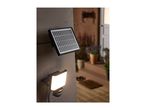 Solar-powered outdoor spotlight with motion sensor and separate solar panel mounted on a wall.