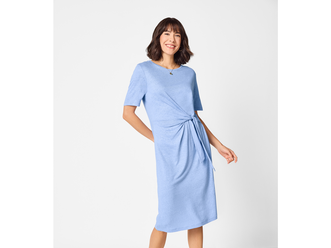 Mulher sorridente com um vestido azul claro de manga curta e um nó lateral.