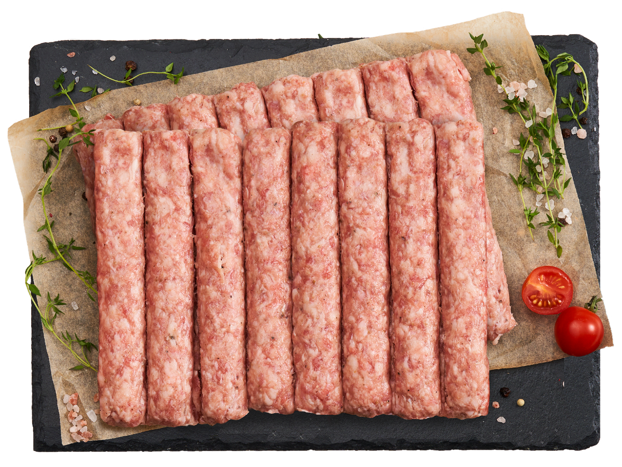 Сурови кебапчета, подредени върху хартия за печене, гарнирани с мащерка, сол и чери домати.