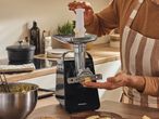 A person using a meat grinder to make cookies in a kitchen setting.