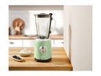 A green SilverCrest blender on a wooden counter with blueberries and cream.