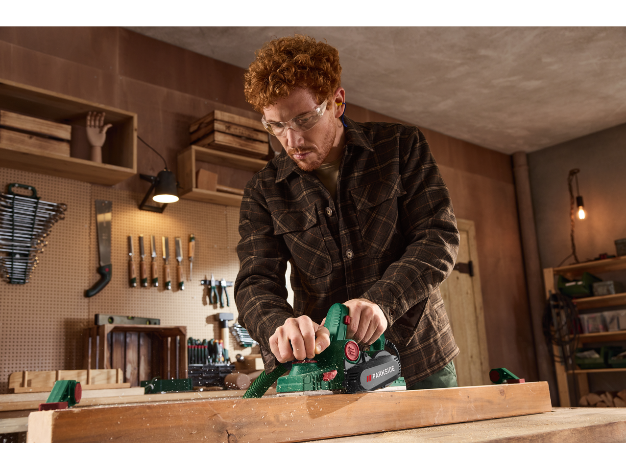 Man using a Parkside® 750W Electric Planer on wood in a workshop.