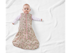 Baby in a floral sleep sack on a white blanket