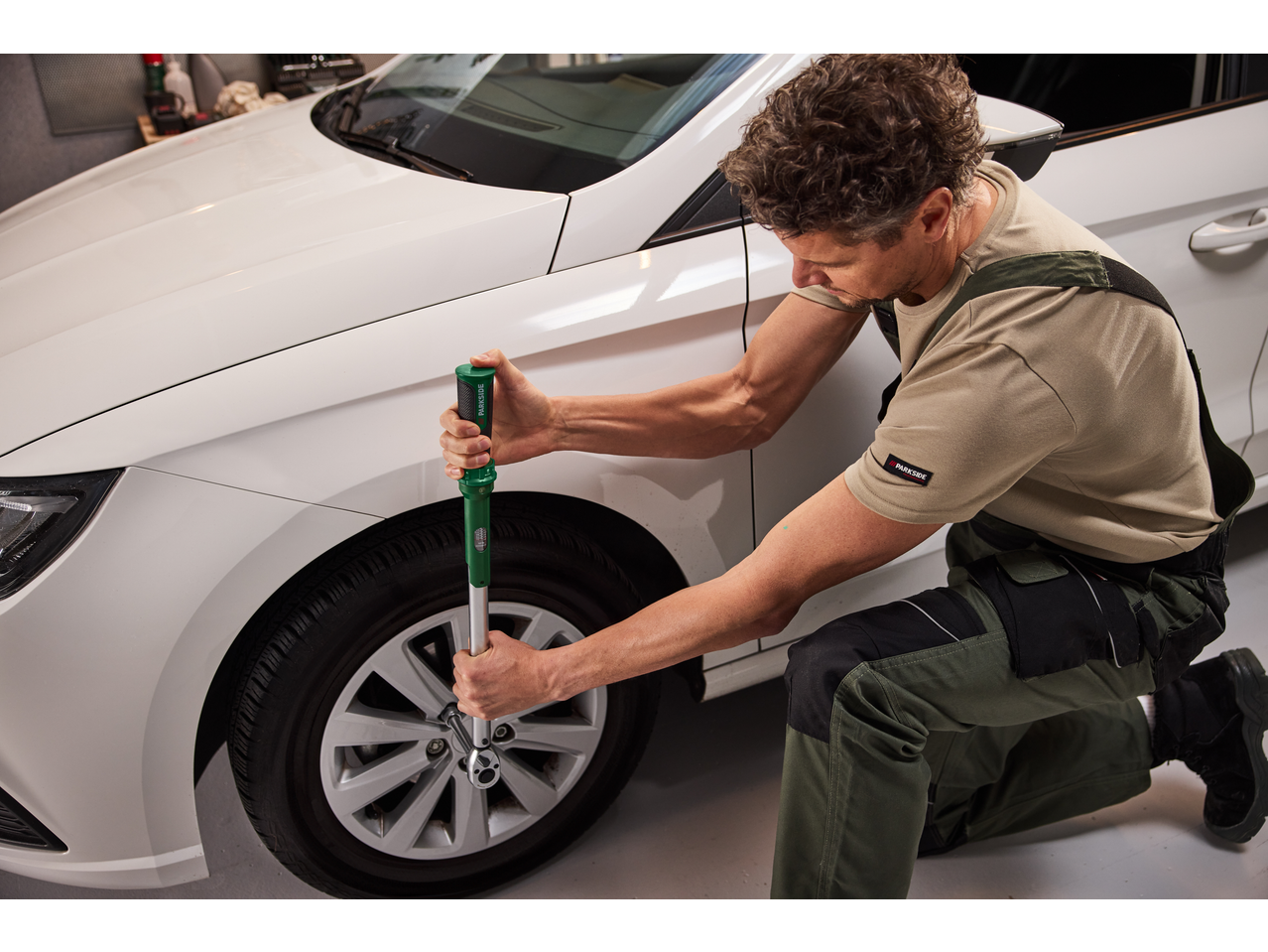 Moški uporablja momentni ključ PARKSIDE za privijanje avtomobilskega kolesa.