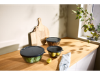 Bancada de cozinha com recipientes de armazenamento de alimentos, tábuas de corte e um limão.