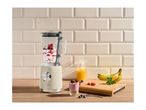 Retro-style blender on a kitchen counter next to fresh fruit, juice, and a smoothie.