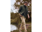 Homem com colete acolchoado verde Livergy e calças bege junto a um lago.