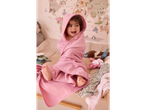 A baby in a pink hooded towel sitting on a changing table with a world map on the wall.