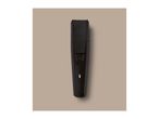 Black beard trimmer with a textured grip and a white indicator light, on a beige background.